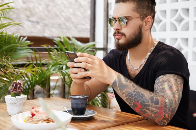 Bärtiger stilvoller Mann, der im Café sitzt