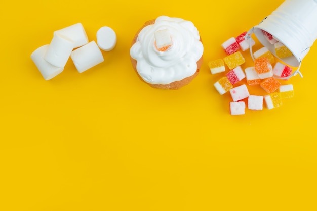 Baiser und Marshmallows von oben mit Marmelade auf gelber, zuckersüßer Bonbonfarbe