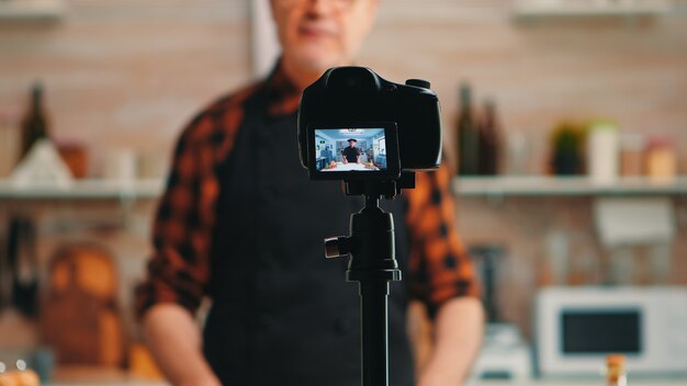 Baker präsentiert die Verwendung von Weizenmehl während der Aufnahme eines Video-Tutorials. Pensionierter Blogger-Koch-Influencer, der Internet-Technologie verwendet, kommuniziert und Blogging in sozialen Medien mit digitaler Ausrüstung fotografiert