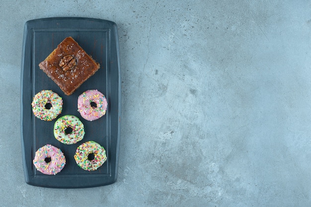 Bakhlava und Donuts auf einem Marinebrett auf Marmoroberfläche