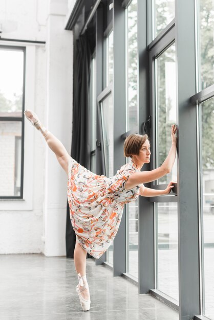 Ballerina, die Aufstellung nahe der geschlossenen Tür ausdehnt