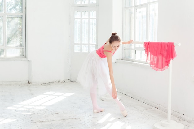Ballerina, die in Spitzenschuhen am weißen hölzernen Pavillon aufwirft