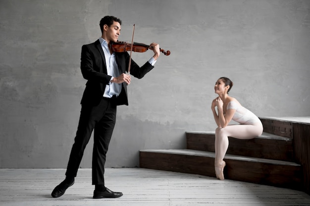 Ballerina hört dem männlichen Musiker zu, der Geige spielt