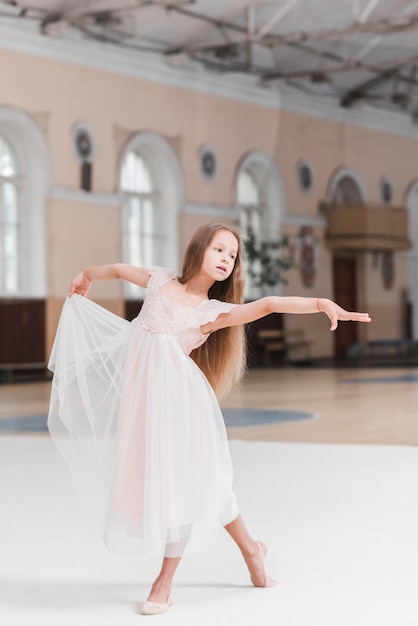 Kostenloses Foto ballerina im rosa kleidertanzen auf tanzfläche