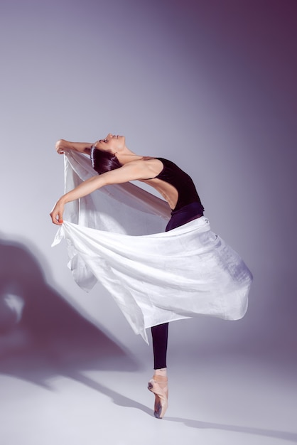 Ballerina im schwarzen Outfit posiert auf Zehen.