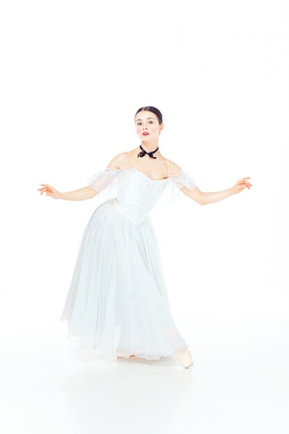 Ballerina im weißen Kleid, das auf Spitzenschuhen aufwirft, Studioweiß.