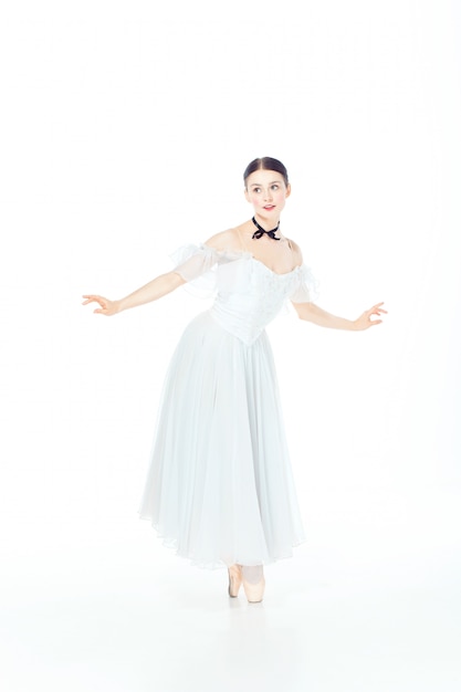 Ballerina im weißen Kleid, das auf Spitzenschuhen aufwirft, Studioweiß.