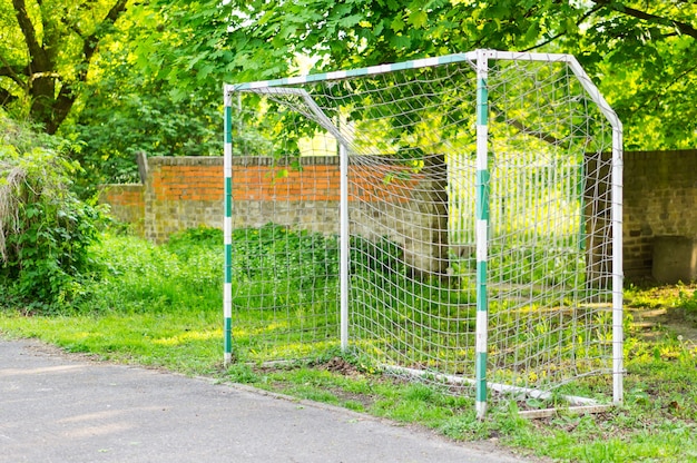 Balltor in einem Fußballfeld im Park, umgeben von grünen Bäumen