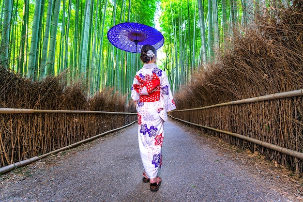 Bambuswald. asiatische frau, die traditionellen japanischen kimono am bambuswald in kyoto, japan trägt.