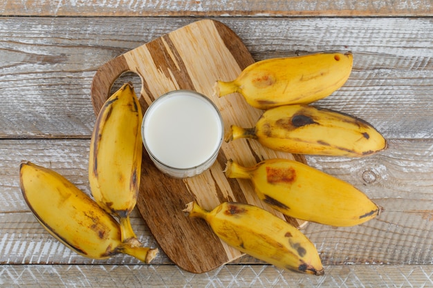 Bananen mit Milch auf Holz und Schneidebrett,