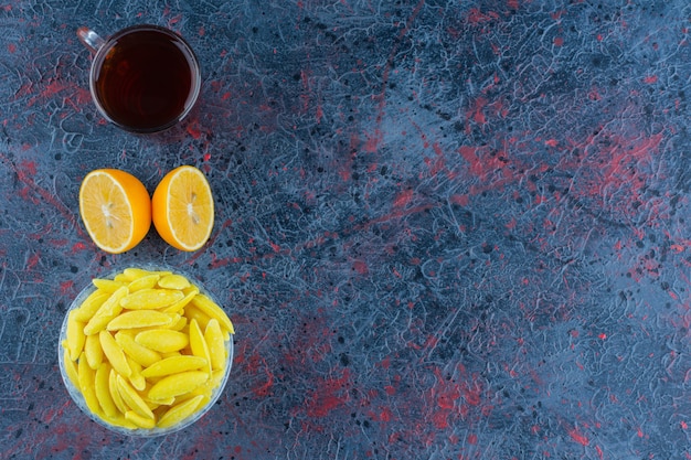 Bananenförmige Kaubonbons mit einer Tasse schwarzen Tee und gehackter Zitrone.