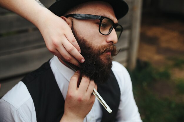 Barbier rasiert einen bärtigen Mann in Vintage-Atmosphäre