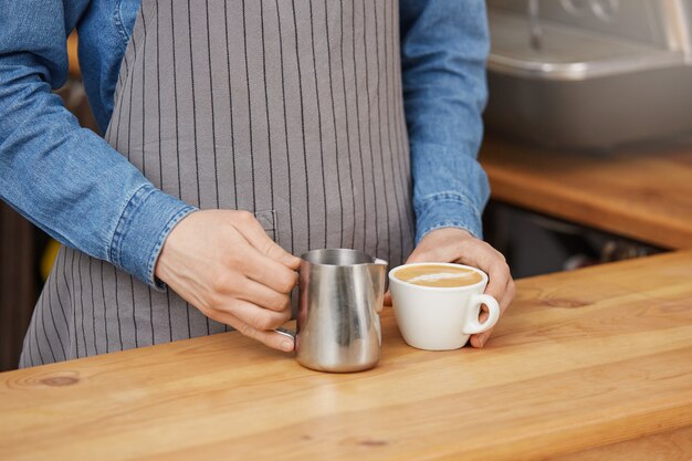 Barista beendete letztere Kunst und hielt weiße Tasse und Krug.