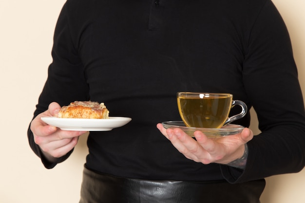 Barista im schwarzen Anzug mit Kuchen und heißer Tasse grünem Tee