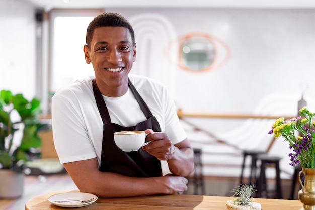 Kostenloses Foto barista mit mittlerem schuss, der eine kaffeetasse hält