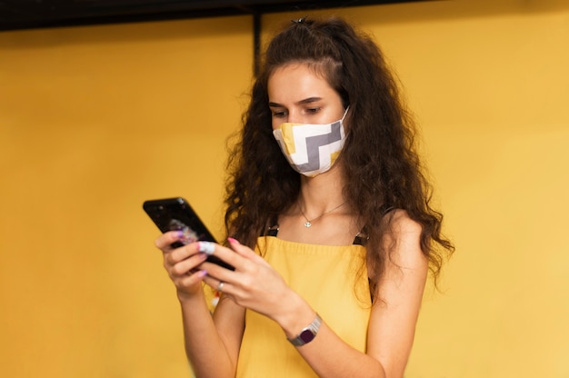 Kostenloses Foto barista trägt eine medizinische maske, während sie ihr telefon überprüft