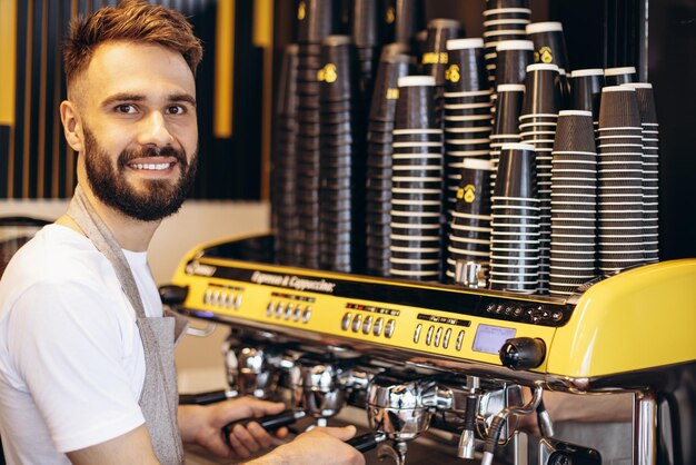 Barista wärmt Milch an einer Kaffeemaschine auf