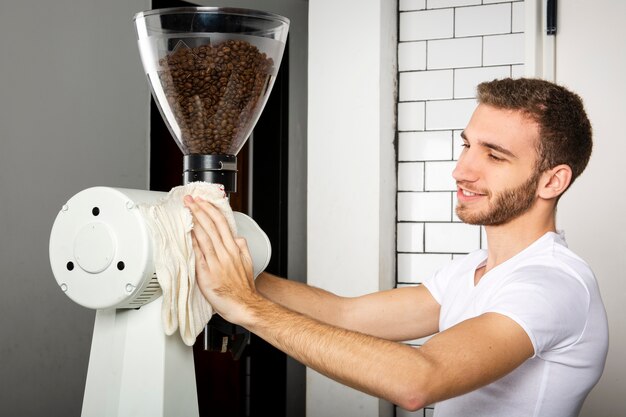 Barista wischt die Kaffeemaschine mit einem Tuch ab