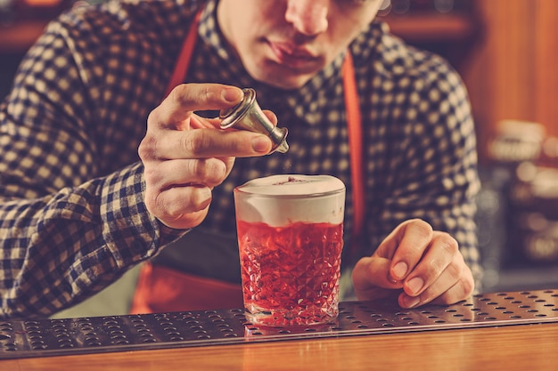 Barkeeper macht einen alkoholischen Cocktail an der Theke an der Bar