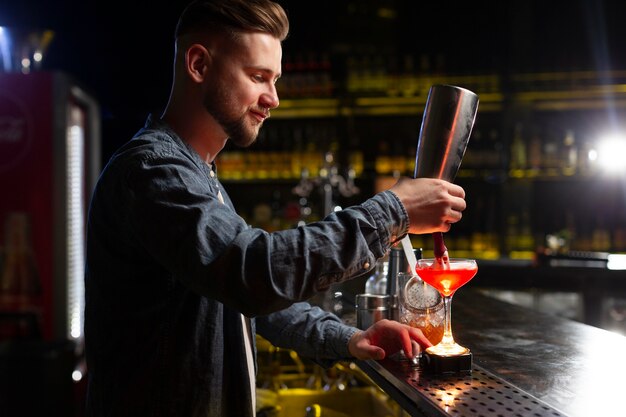 Barkeeper macht einen Cocktail mit einem Shaker