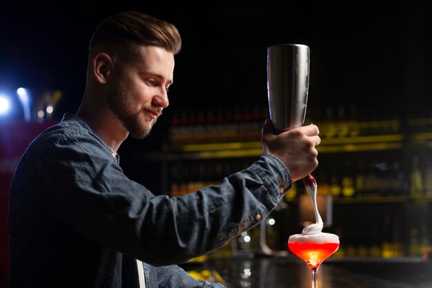 Barkeeper macht einen Cocktail mit einem Shaker