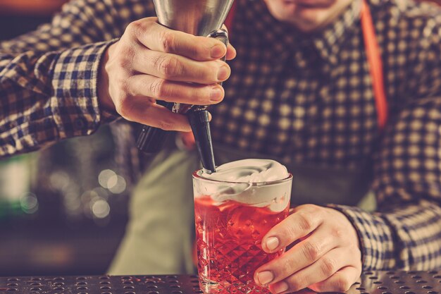 Barmann macht einen alkoholischen Cocktail an der Theke an der Bar