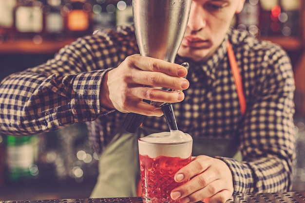 Barmann macht einen alkoholischen cocktail an der theke an der bar