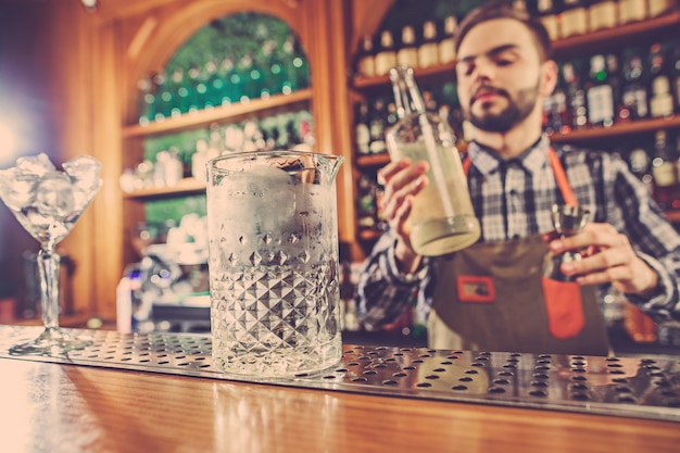 Barmann macht einen alkoholischen Cocktail an der Theke an der Bar