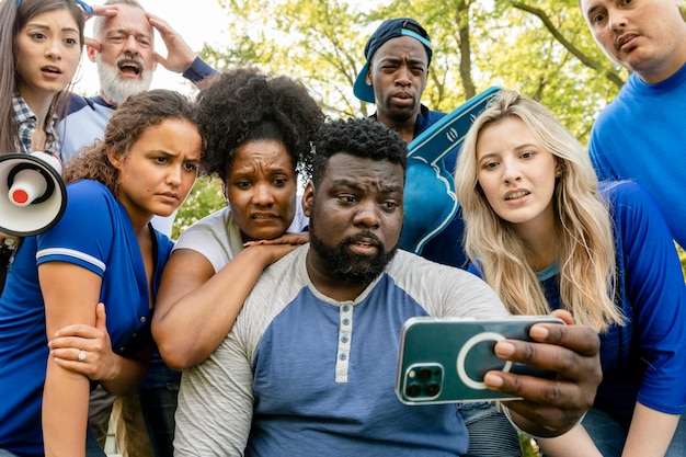 Kostenloses Foto baseball-fans sehen ihrem team beim verlieren des spiels auf einem telefon zu