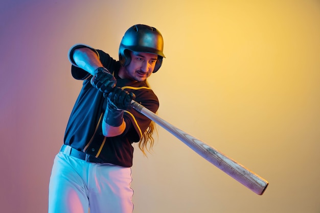 Baseballspieler, Krug in einer schwarzen Uniform, die zuversichtlich auf Gradientenhintergrund im Neonlicht aufwirft.