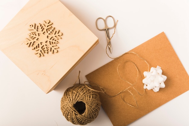 Basteln Sie Papier in der Nähe von Bogen, Kasten, Schere, Ornamentschneeflocke und Drehungen