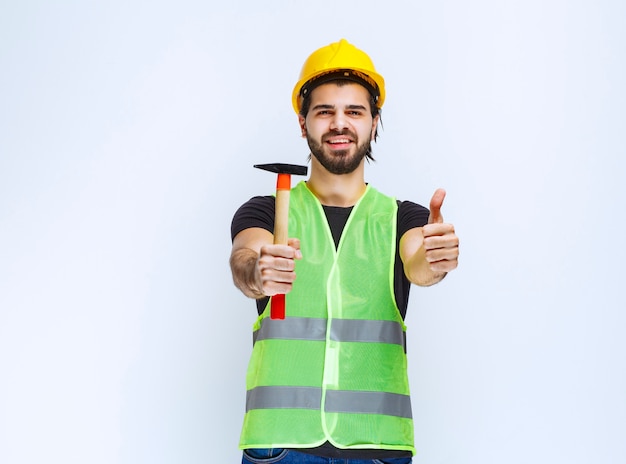 Bauarbeiter, der einen Klauenhammer hält und Freudenzeichen zeigt.