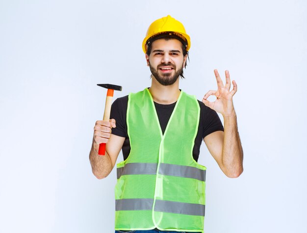 Bauarbeiter, der einen Klauenhammer hält und Freudenzeichen zeigt.