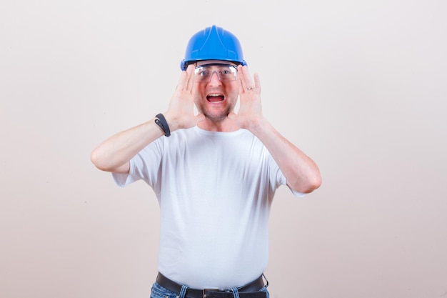 Bauarbeiter in T-Shirt, Jeans, Helm schreien oder etwas ankündigen