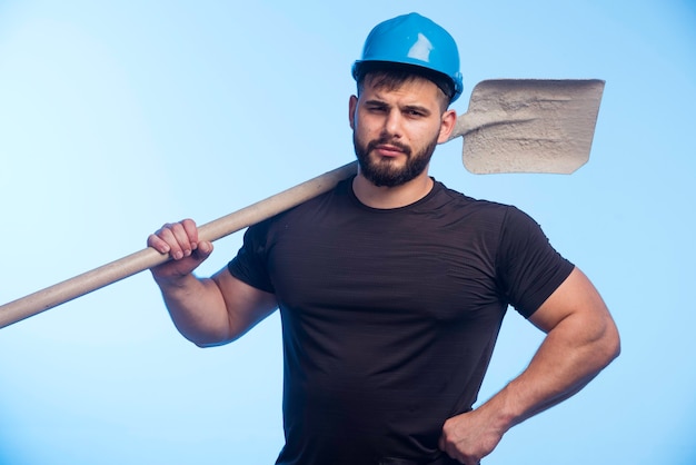 Bauarbeiter mit blauem Helm, der die Ausrüstung hält