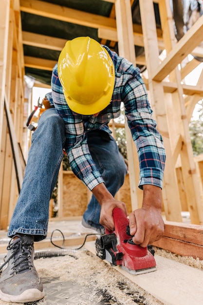 Bauarbeiter mit Schutzhelm, der Holzstück abschleift