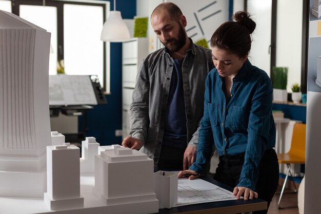 Bauarchitektenteam, das im Schreibtischbüro an Blaupause arbeitet