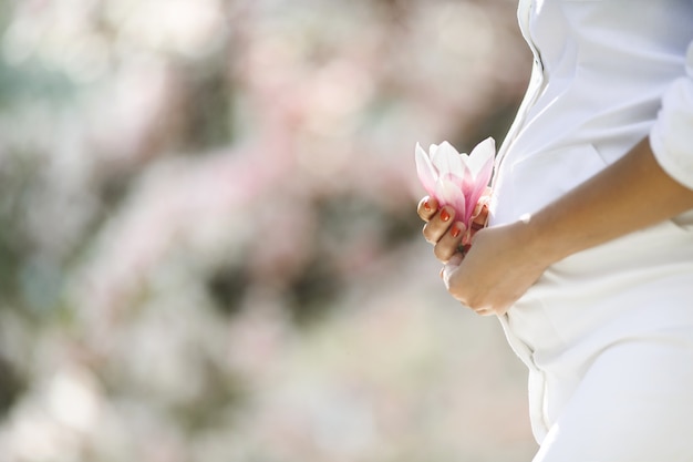 Bauch einer schwangeren Frau und einer Blume