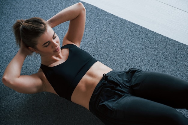 Bauchmuskeln auf dem Boden im Fitnessstudio machen. Schöne weibliche Fitnessfrau