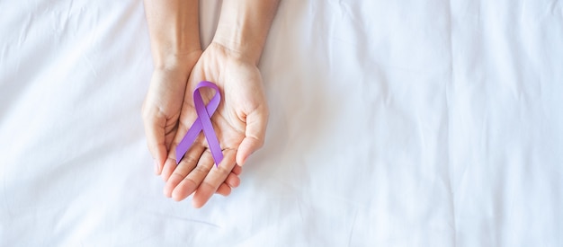 Bauchspeicheldrüsenkrebs, hoden, welt-alzheimer, epilepsie, lupus und gewalttag bewusstseinsmonat, frau, die lila band hält, um das leben der menschen zu unterstützen. konzept für das gesundheitswesen und den weltkrebstag