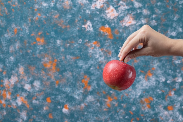 Bauer, der einen roten Apfel auf Blau hält.