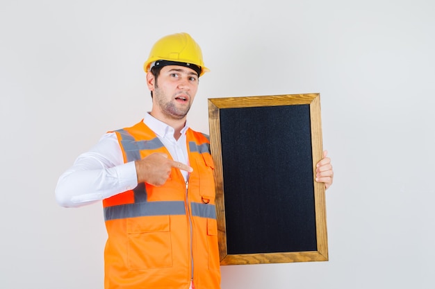 Baumeistermann, der Finger auf Tafel im Hemd, Uniform zeigt. Vorderansicht.