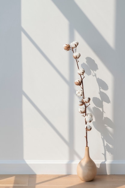 Kostenloses Foto baumwollblume in einer vase auf einem holzboden