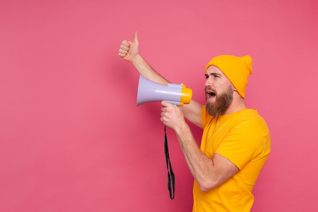 Beachtung! Europäischer Mann, der im Megaphon auf rosa Hintergrund schreit