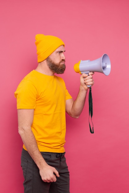 Kostenloses Foto beachtung! verärgerter europäischer mann, der im megaphon auf rosa hintergrund schreit