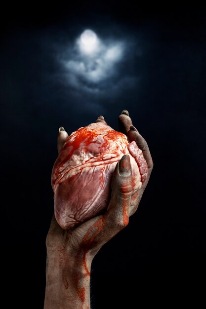 Beängstigende weibliche Zombiehand, die ein Herz hält