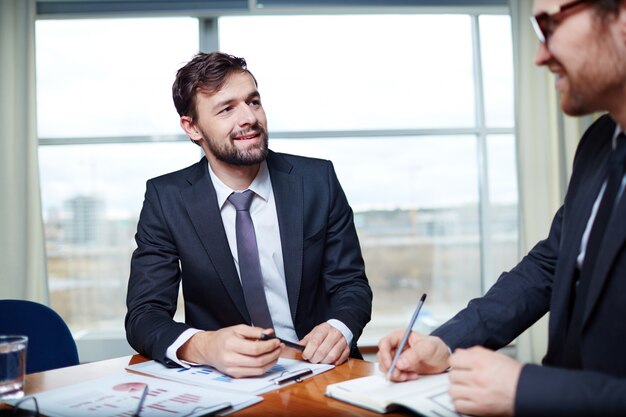 Bearded Exekutive einen Stift in der Sitzung halten