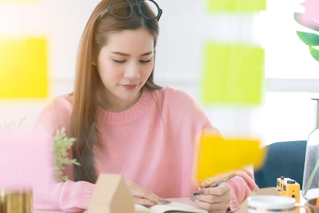 Beauty smart asiatische weibliche rosa farbe kleid lässige arbeit zu hause mit klebriger papiernotiz und datendokument treffen sich auf besprechungstisch