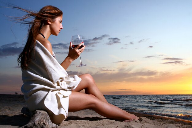 Beautyful junge Frau trinkt Wein am Strand