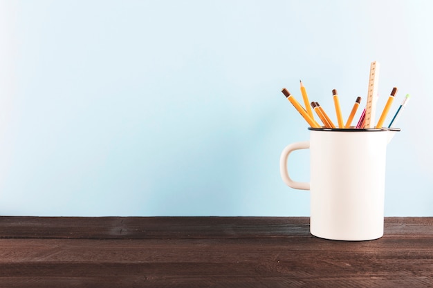 Becher mit Bleistiften und Machthaber auf Tabelle